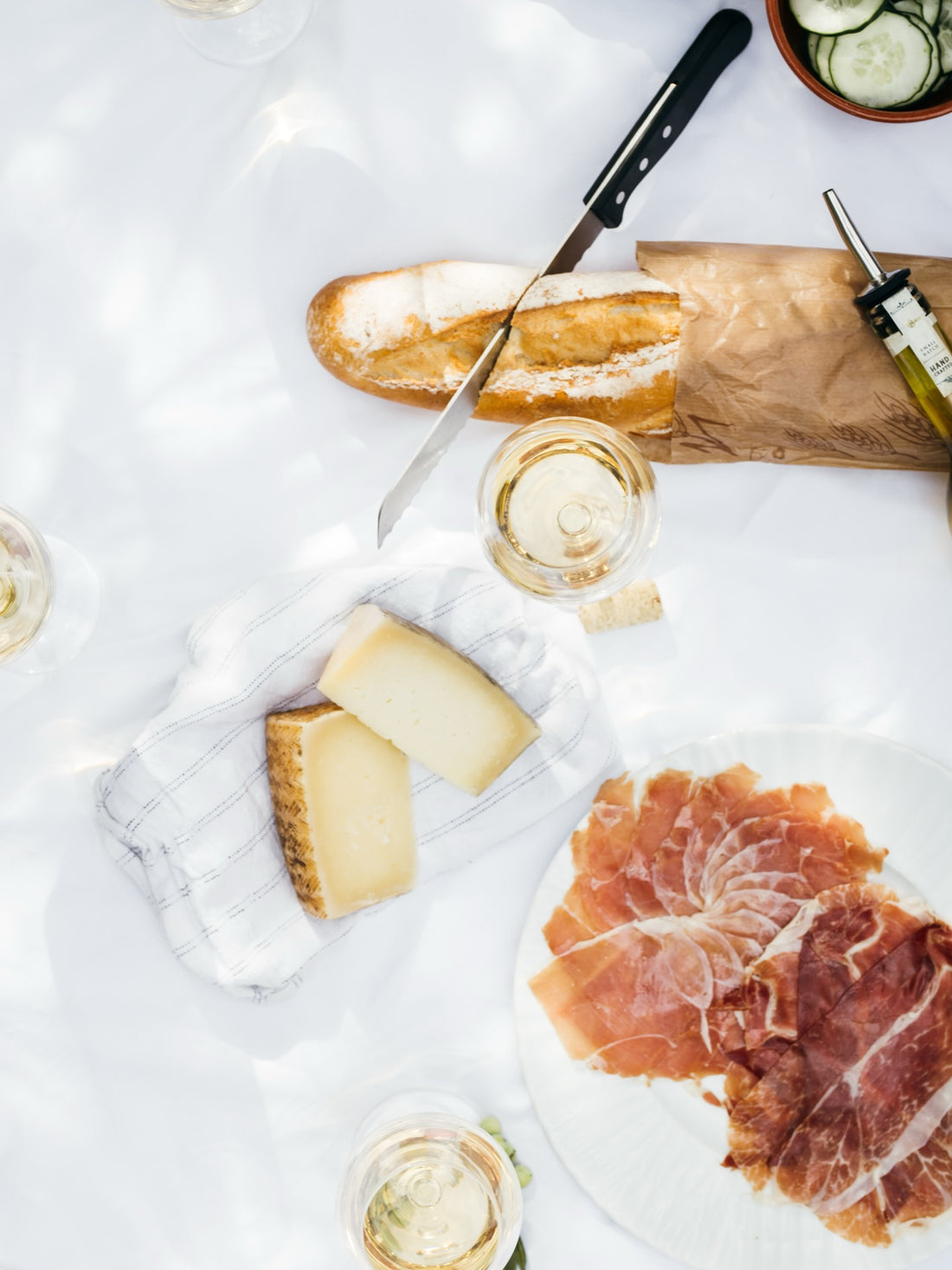 A crusty baguette and a glass of white wine on a bright table